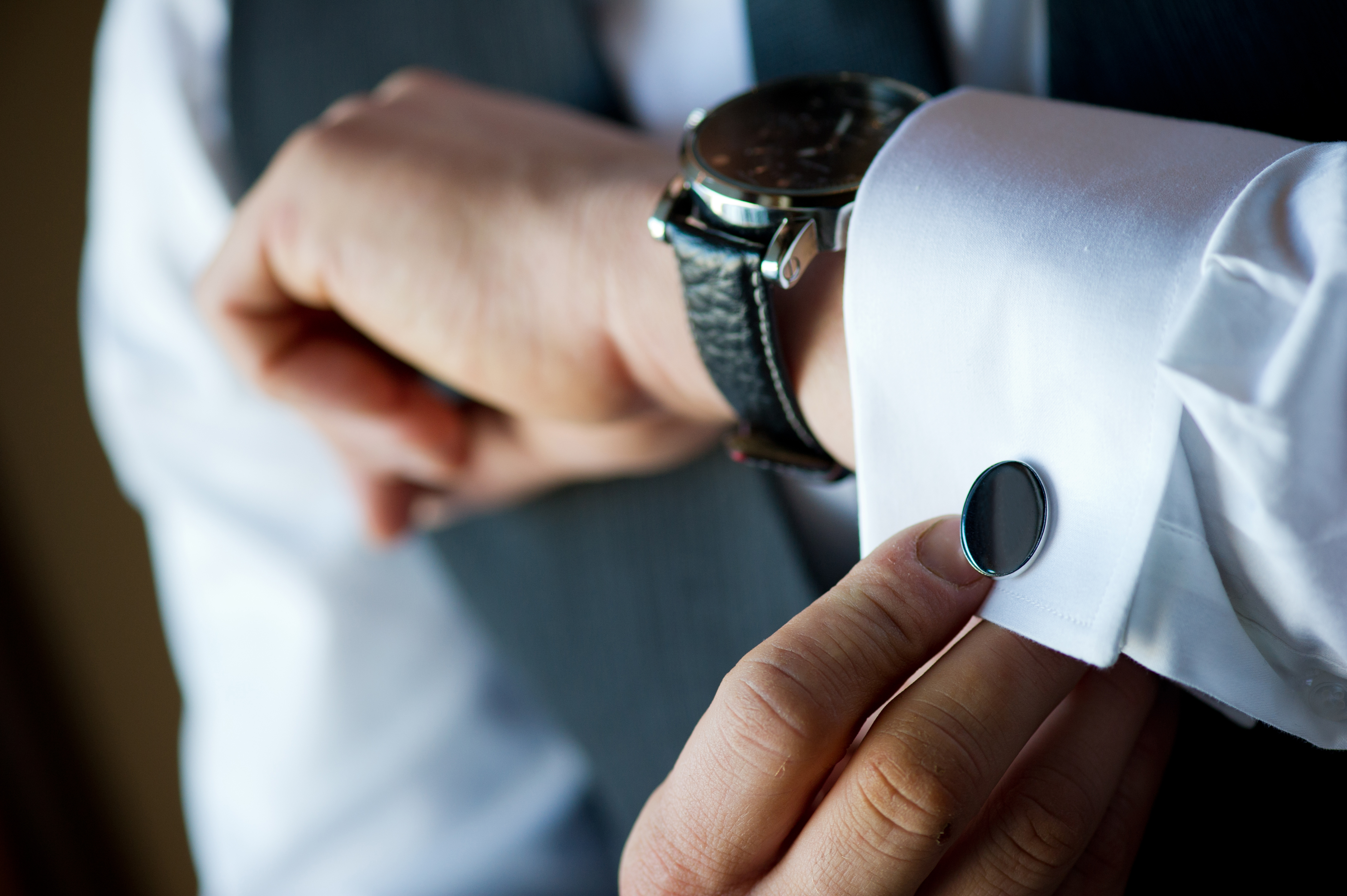 A white suit sleeve with a button to the right of the model's watch